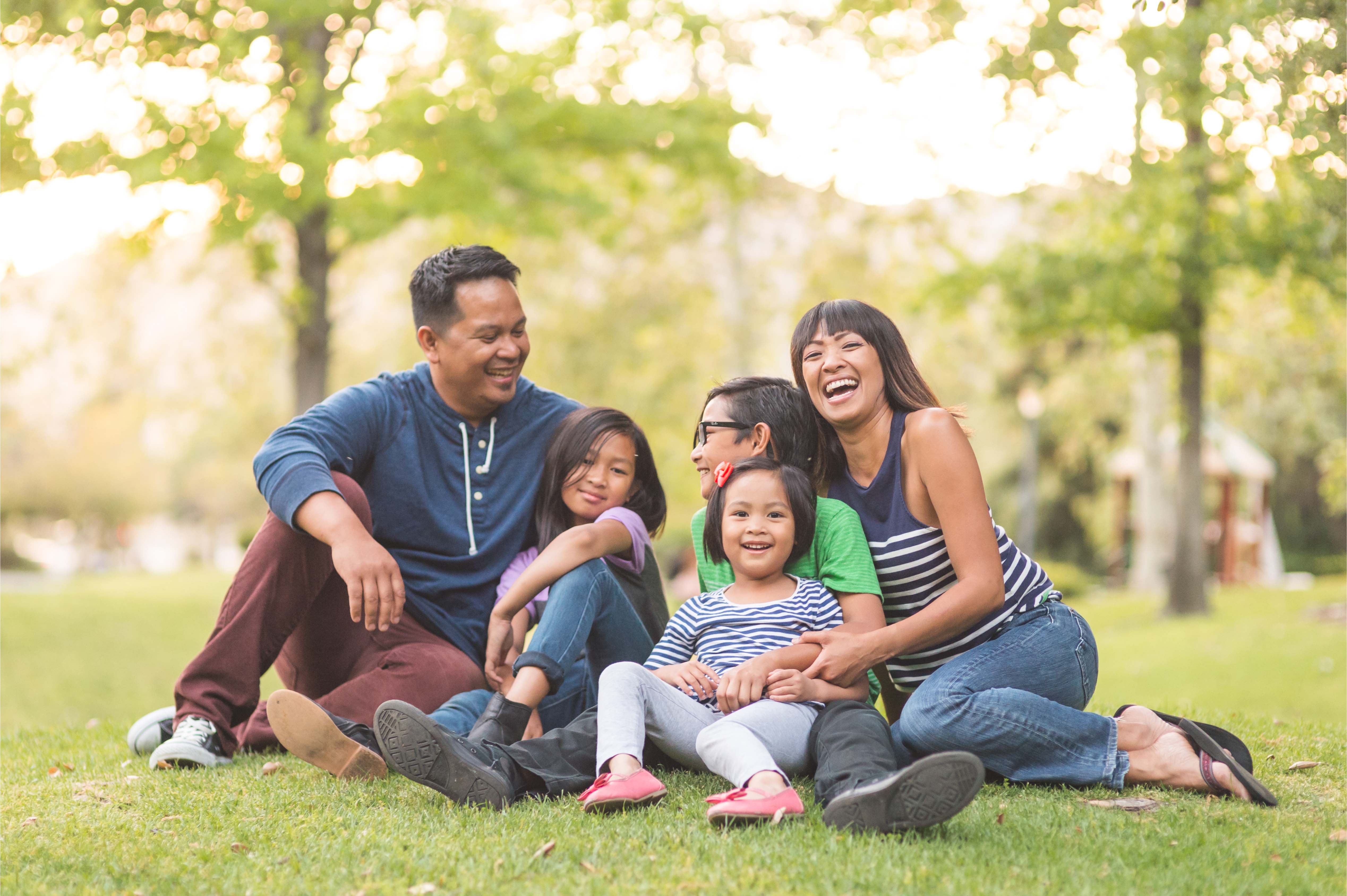 ilipino family laughing together outdoors, symbolizing health, happiness, and wellbeing.