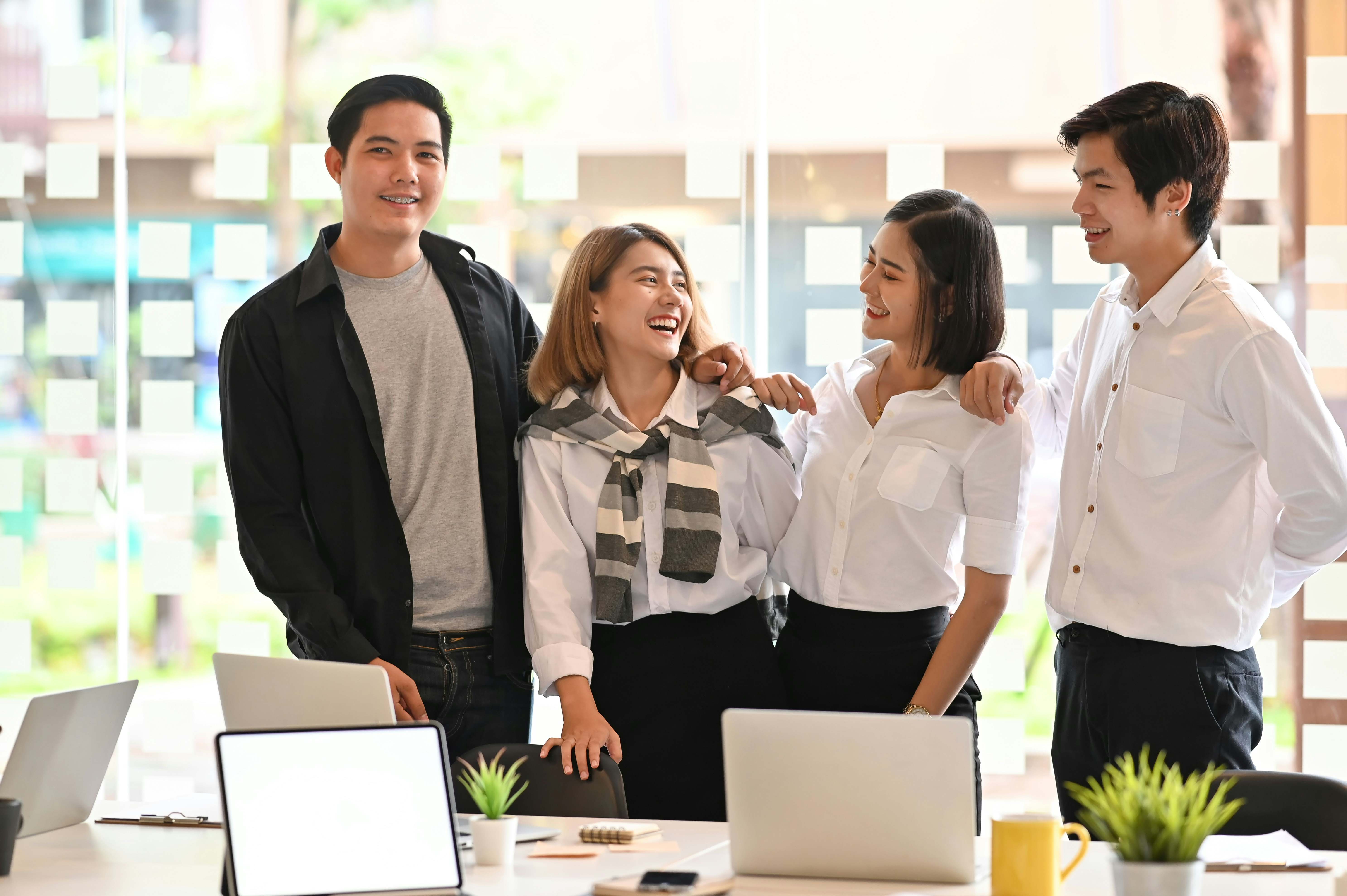 A group of colleagues standing together, smiling and interacting, representing connection, belonging, and a positive workplace culture.