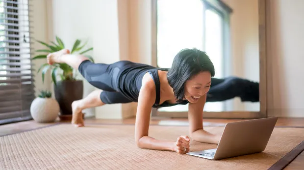 Woman doing yoga while looking at a laptop