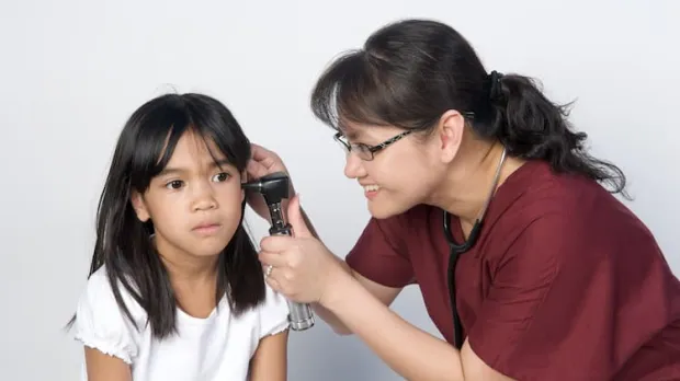 Doctor taking temperature in young girl's ear Doctor taking temperature in young girl's ear