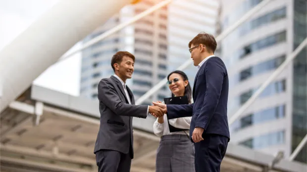 Business leaders shaking hands in a city environment Business professionals shaking hands in a modern city setting, symbolising leadership, trust, and key person protection.