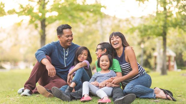 ilipino family laughing together outdoors, symbolizing health, happiness, and wellbeing.