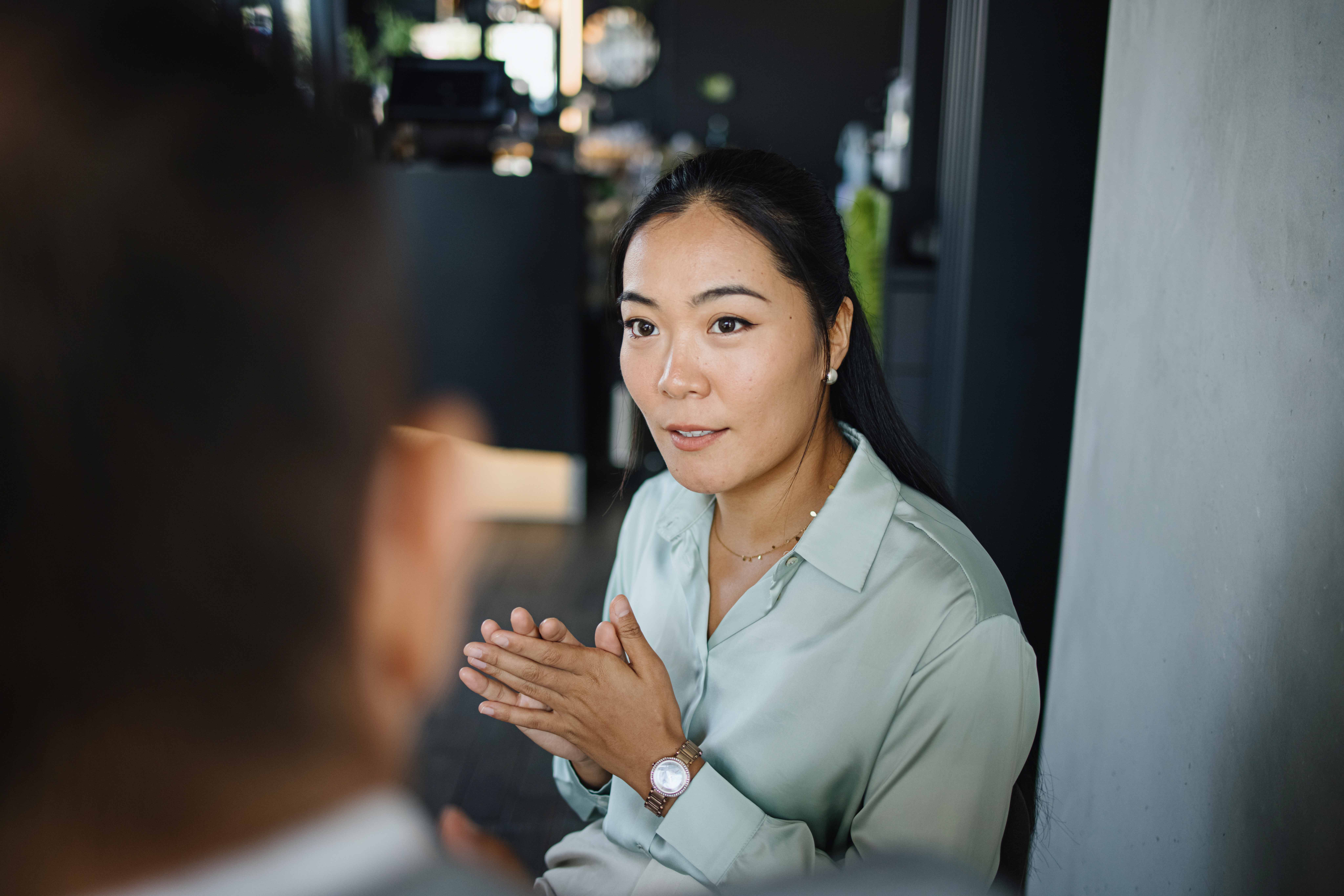 Professional woman attentively listening and speaking during a business meeting in a modern office setting.