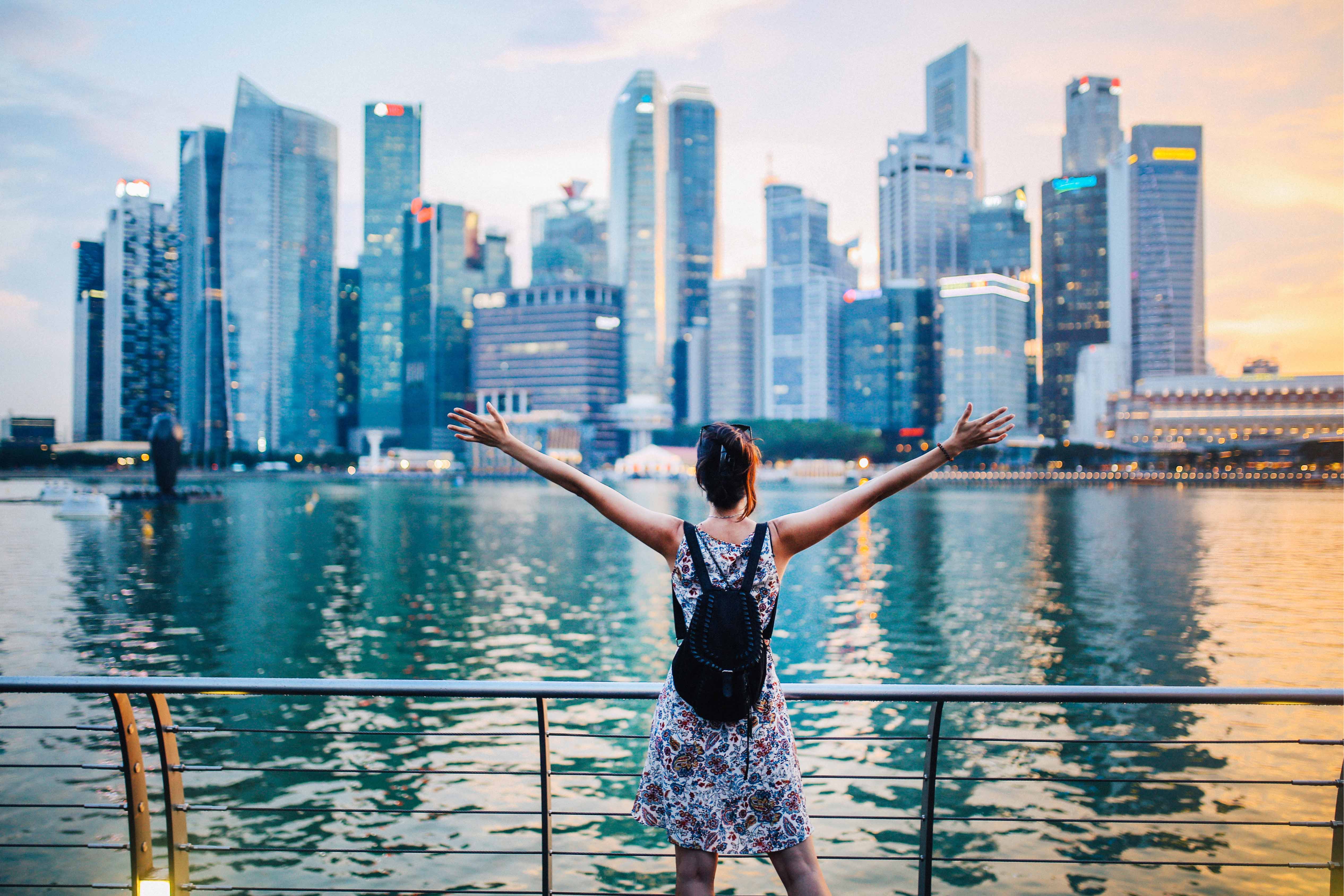 Person with arms raised looking at Singapore’s Marina Bay skyline at sunset, symbolising opportunity and growth