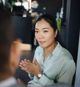 Professional woman attentively listening and speaking during a business meeting in a modern office setting.