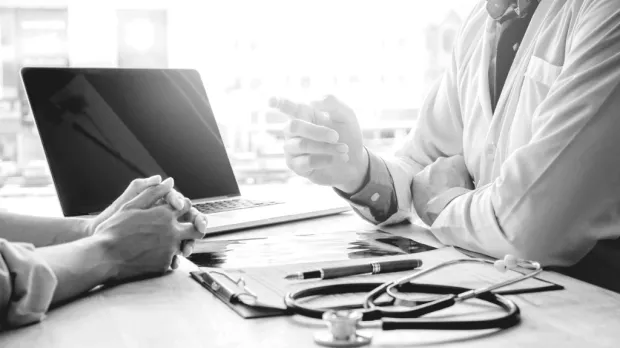 Doctor pointing at a patient over his desk