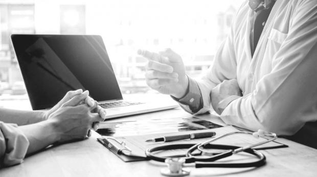 Doctor pointing at a patient over his desk