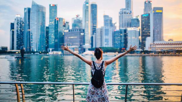 Person with arms raised looking at Singapore’s Marina Bay skyline at sunset, symbolising opportunity and growth