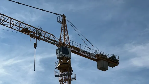 Grúa torre alta en un sitio de construcción con un fondo de cielo azul claro, mostrando maquinaria de la industria de la construcción.