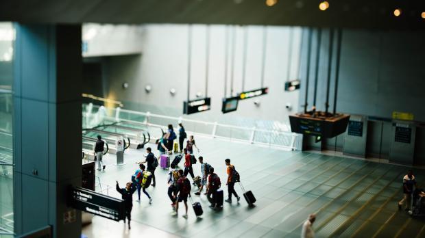 A group of travelers wheel their suitcases through an airport