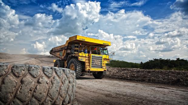 A yellow dumper truck drives down a road
