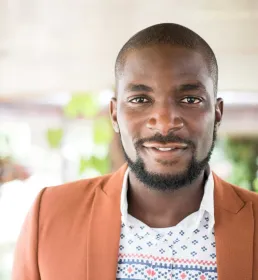 A confident business man wearing a shirt and blazer smiles into the camera