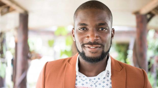 A confident business man wearing a shirt and blazer smiles into the camera