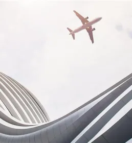 plane flying near modern building