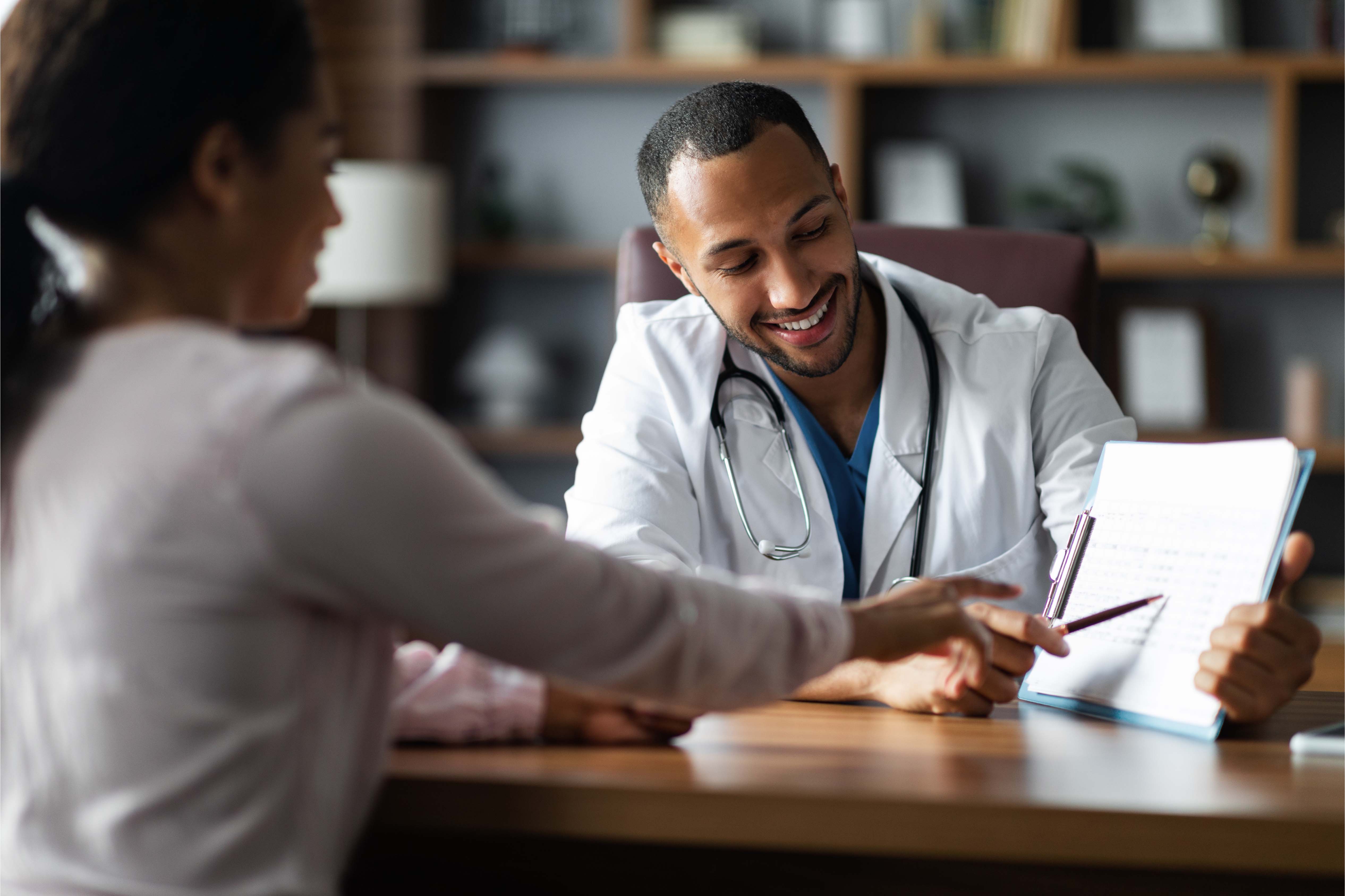 Smiling doctor meeting with a patient, reviewing medical information together — representing access to quality private healthcare through group medical insurance in the UAE.