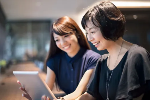 Two women collaborating, using an ipad