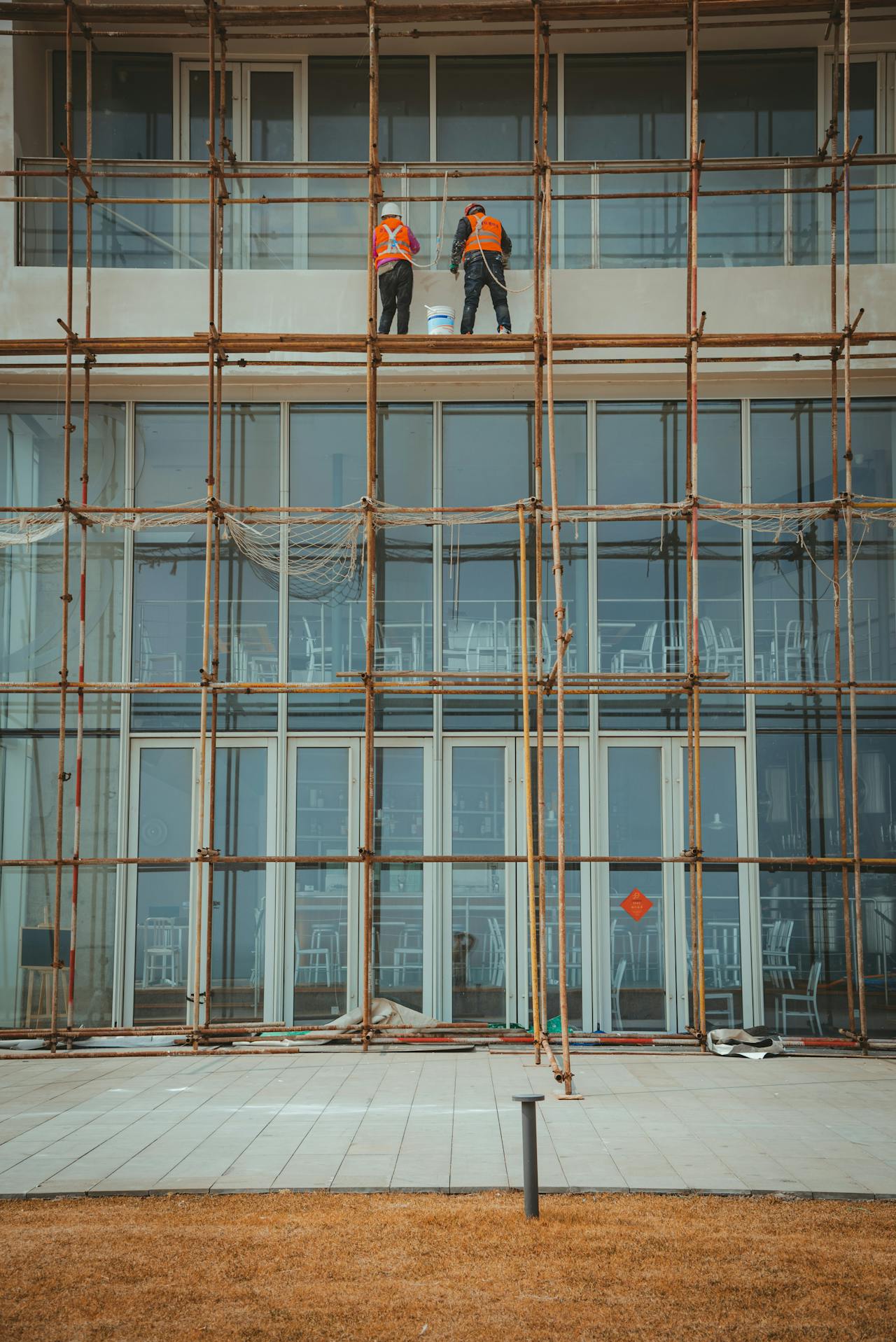 Two contractors on scaffolding working on a building facade