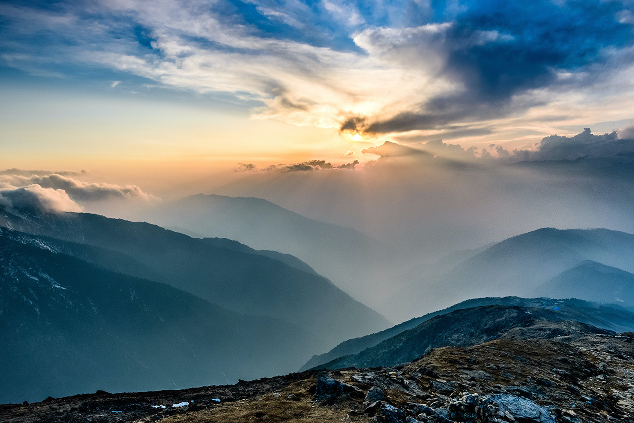 Sun breaking through clouds over mountains