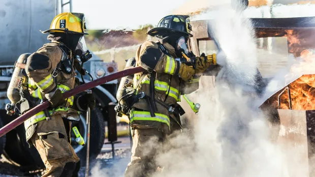 Firefighters using a hose on a fire outdoors